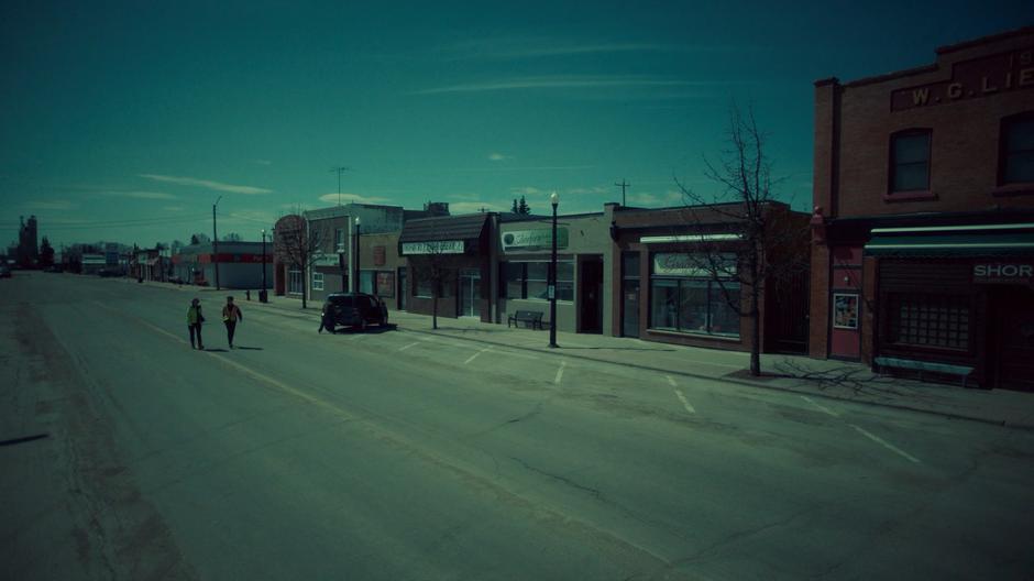 Nicole and Robin walk down the middle of the street as the last of the residents evacuate the town.