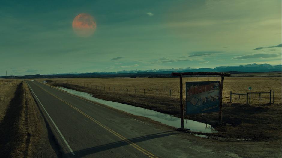 The ominous Pledge Moon sits over the road leading into town.