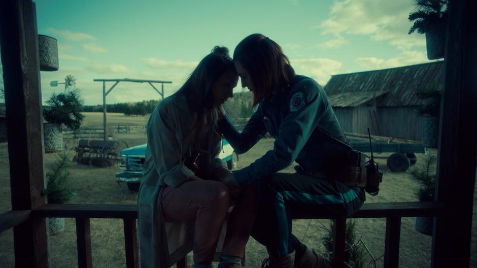 Waverly and Nicole lean their foreheads together while sitting on the porch rail.