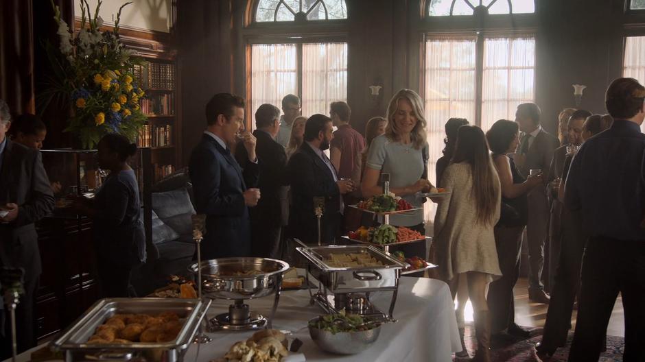 Victor and Janet gather snacks from the food table in the lounge.