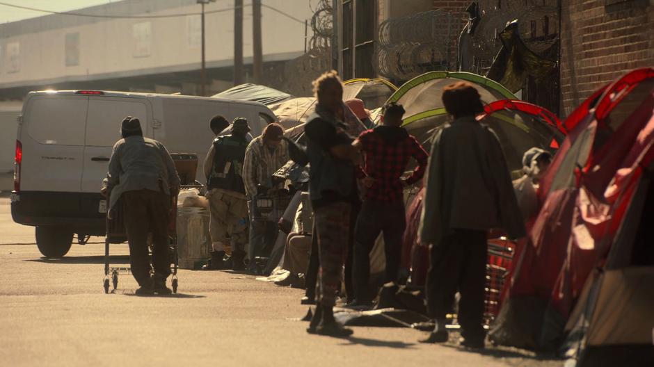 Victor pulls his van to a stop at the side of the alley which is filled with homeless people.