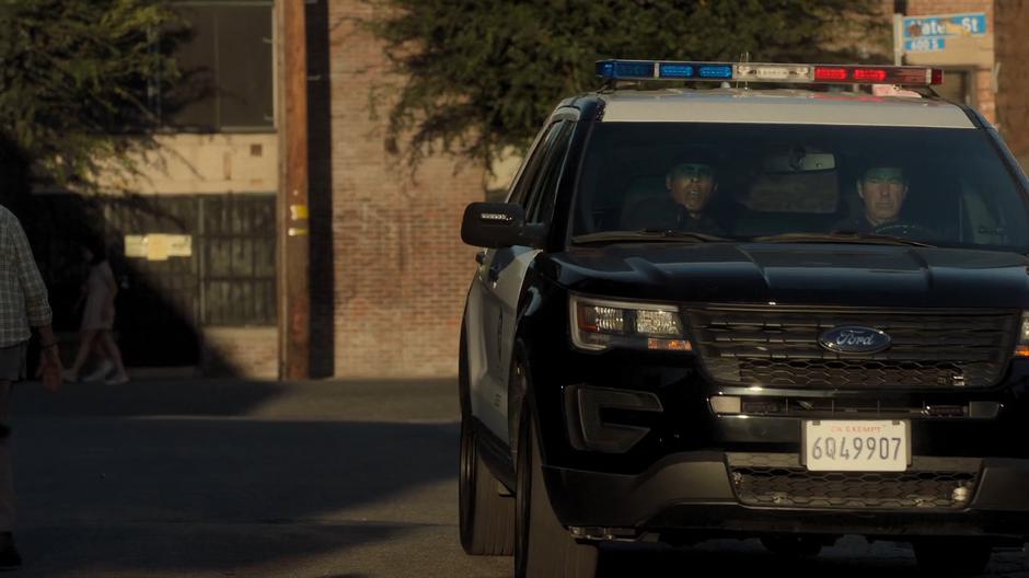 A police car drives down into the alley.