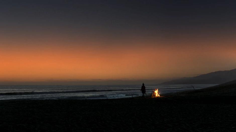 Nico walks around the bonfire she started on the beach.