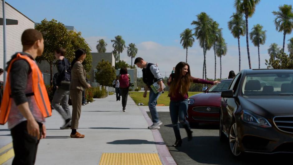 Students exit their cars out front of the school.