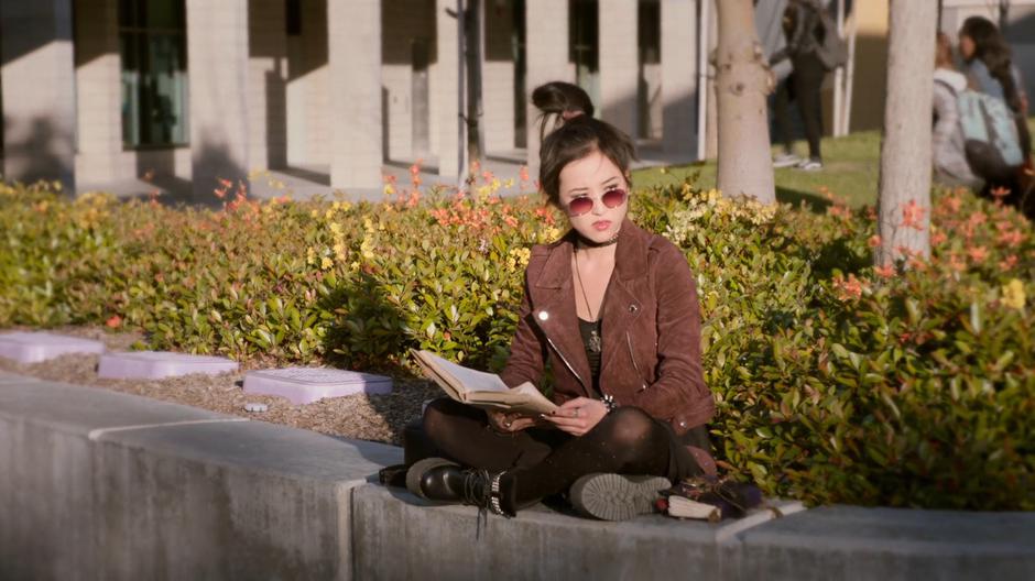 Nico looks up from her book to the students walking past.