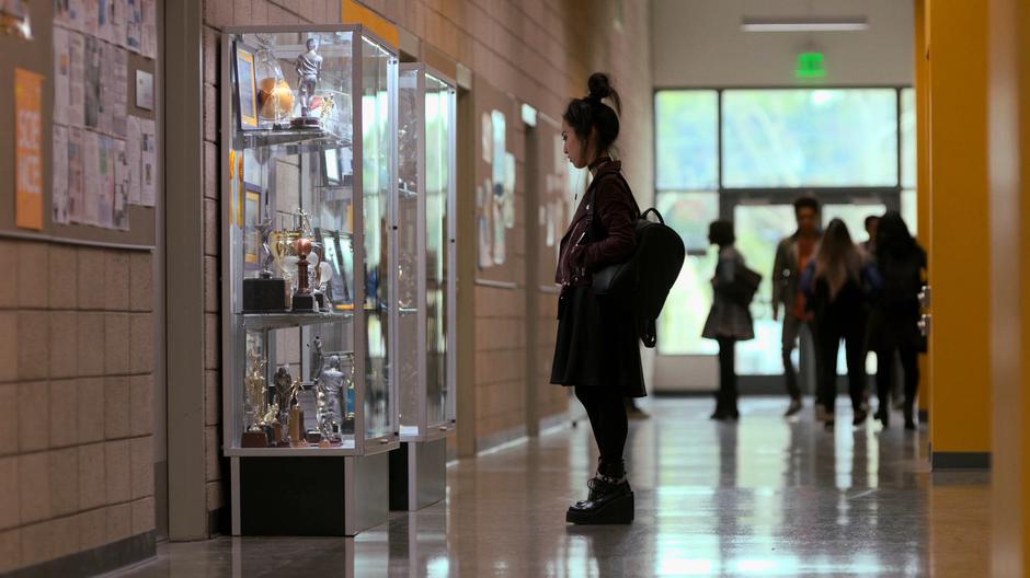 Nico looks into the trophy case at her sister's memorial.