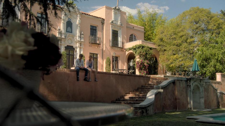 Chase and Karolina sit on the wall above the pool talking.