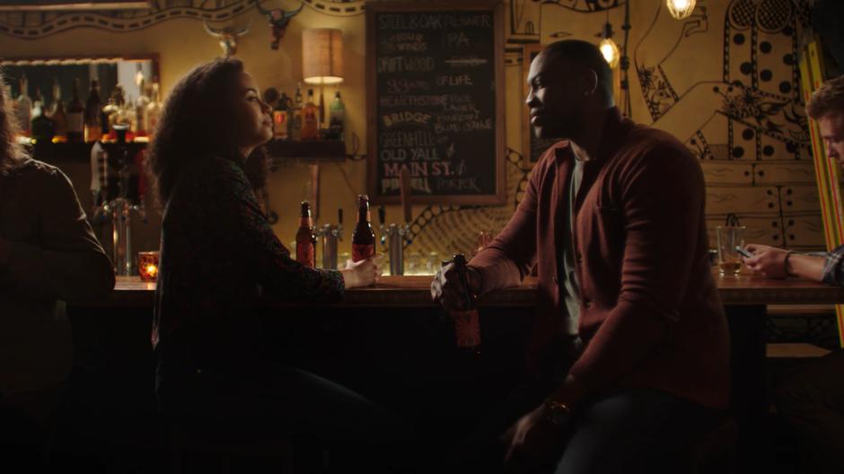 Macy and Galvin drink beers while sitting at the bar.