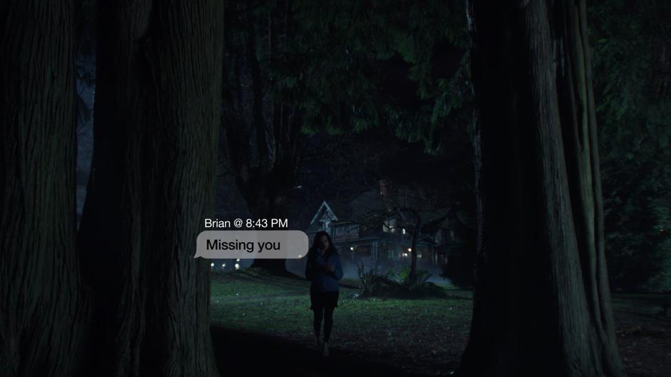 Maggie gets a text from Brian as she is walking into the woods.