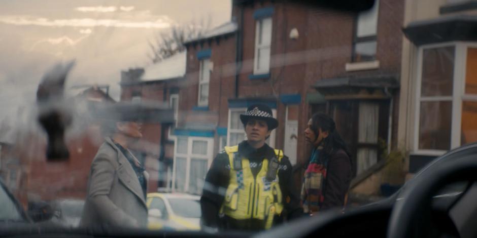 Yasmin looks at the hammer through the windshield of the car while the two women argue behind her.