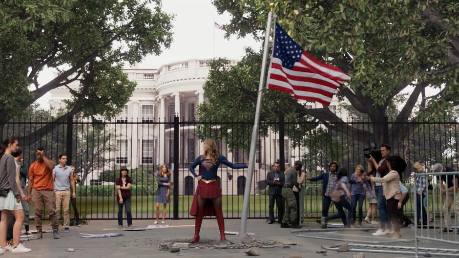 Kara stands between the two sides of the protest holding the flag on the pole.