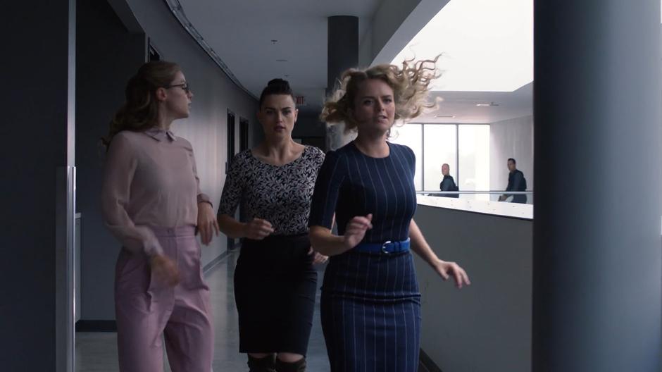 Kara looks over her shoulder as she runs away from the goons with Lena and Eve.