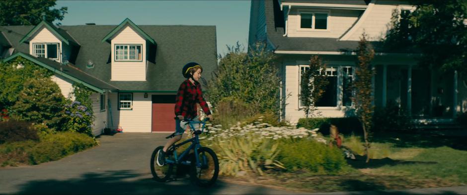 Young Josh rides his bike over to meet Lara Jean.