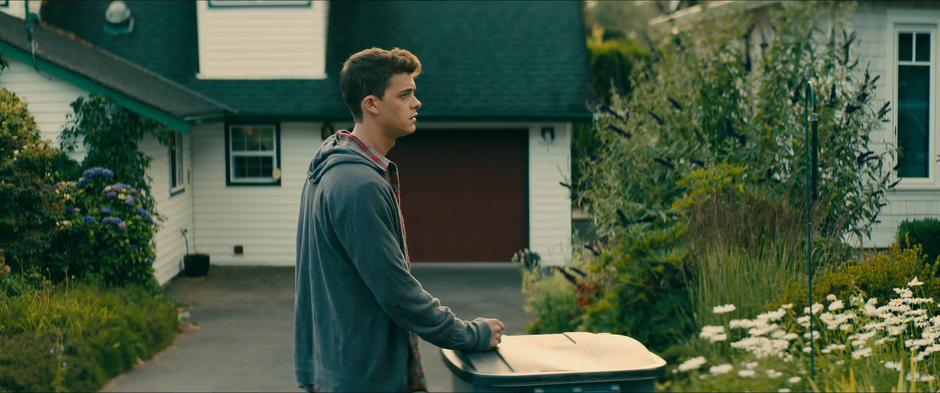 Josh glances over at Lara Jean's house as he takes out the trash.