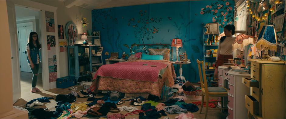 Lara Jean turns around from the window as Kitty looks at the trashed room.