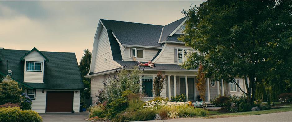 Lara Jean rolls down the small roof outside her window while trying to sneak out to avoid Josh.