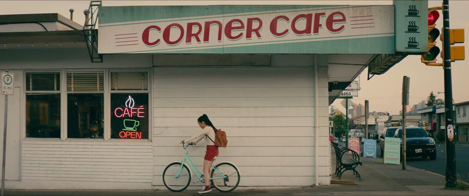 Lara Jean parks her bike on the side of the cafe.