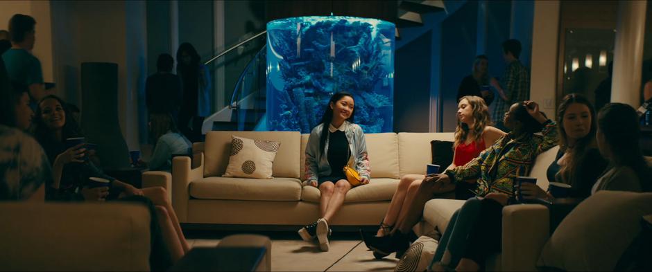 Lara Jean sits down the couch next to Gen.