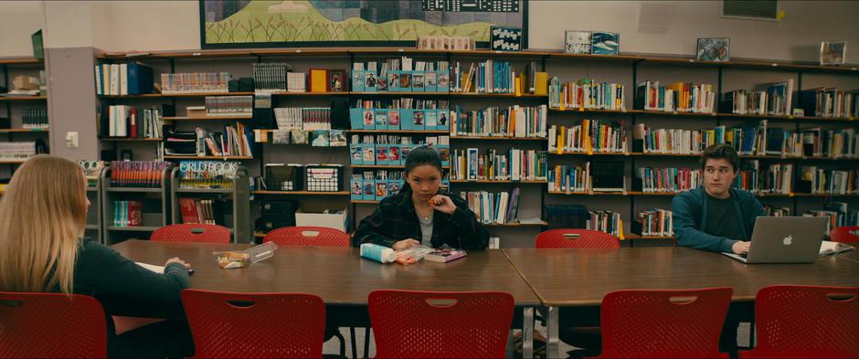 Lara Jean looks up after realizing the carrots she is trying to eat are super loud in the library.