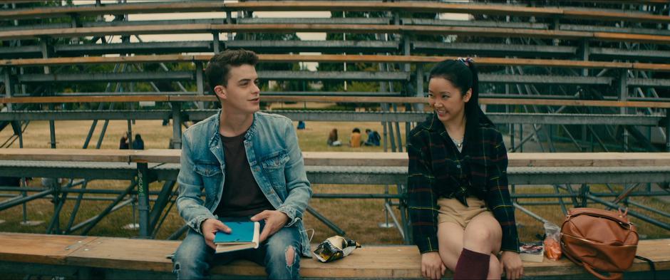 Lara Jean sits down next to Josh on the bleachers during lunch.