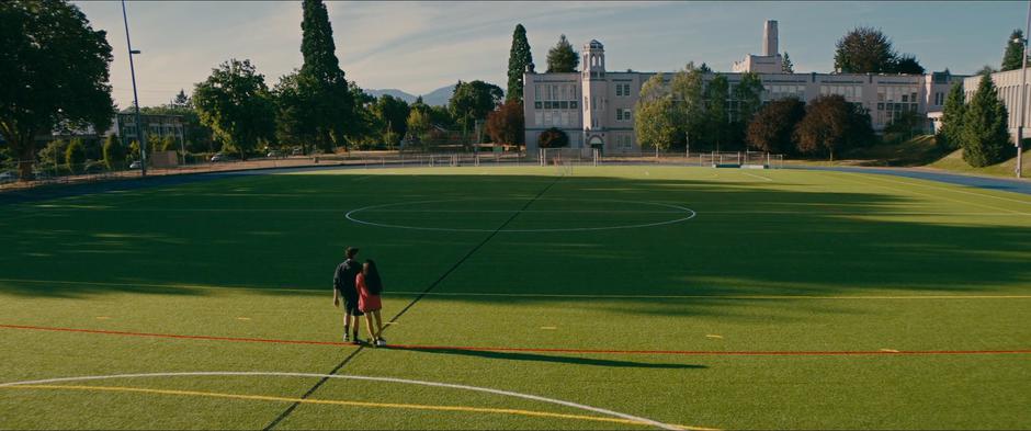 Peter and Lara Jean walk arm-in-arm across the field.