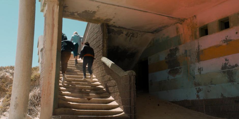 The Doctor and her friends run up the stairs after the robotic guards activate.