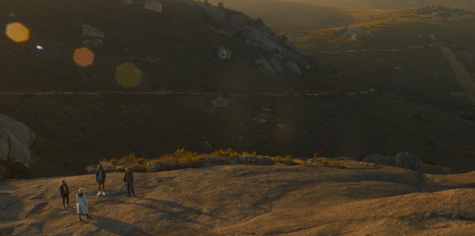 Yasin, the Doctor, Ryan, and Graham look around at the empty landscape they are trapped in.