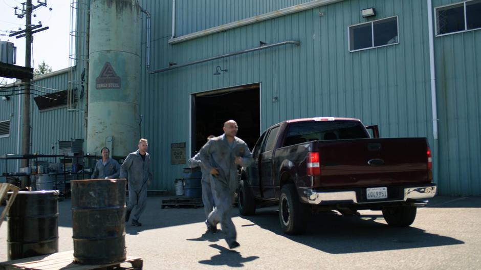 The foundry workers run across the street as Ben and his father pull into the parking lot.