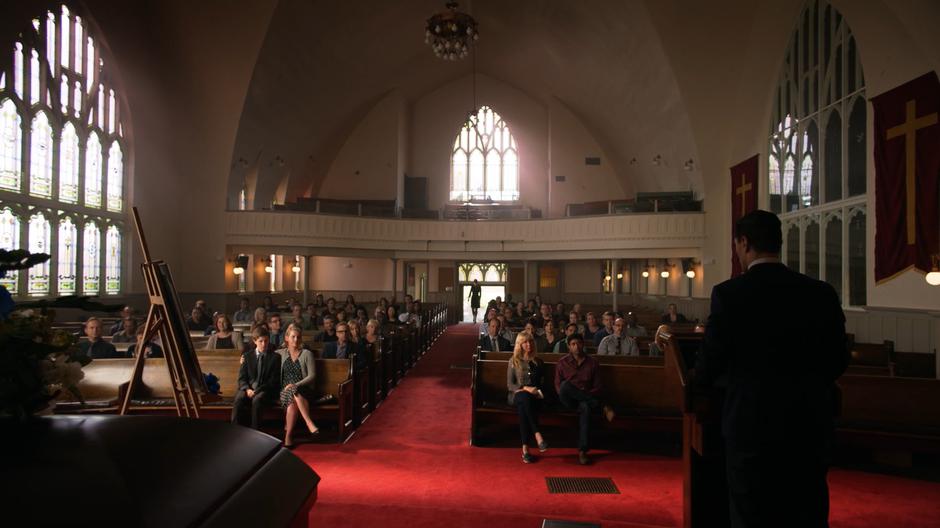 Lena walks in through the back of the church as Ben Lockwood gives his eulogy.