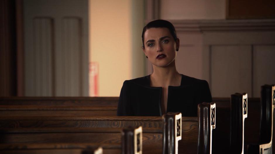 Lena watches the eulogy from the back row of the church.