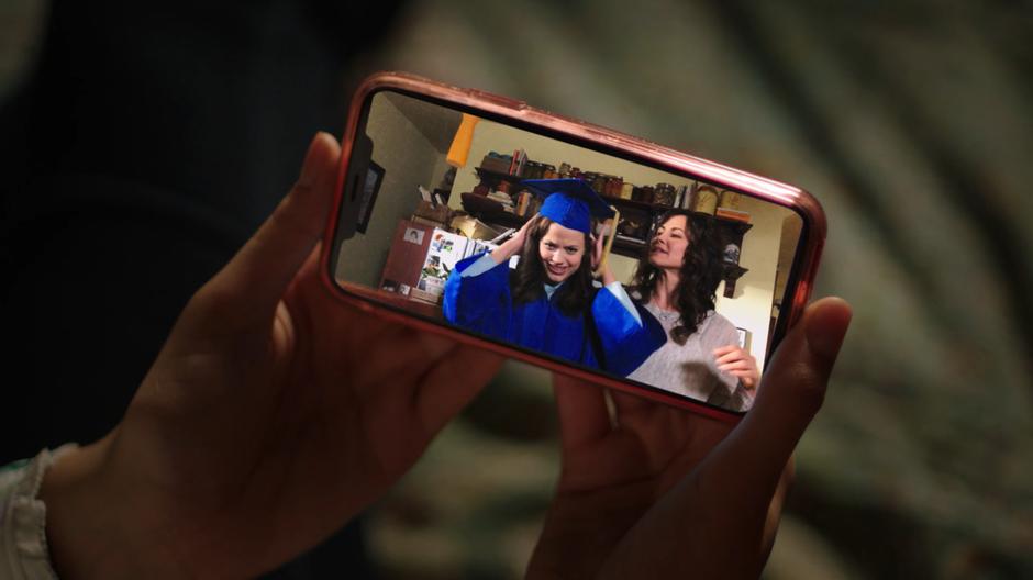 The sisters watch a video of their mother getting Maggie ready for graduation.