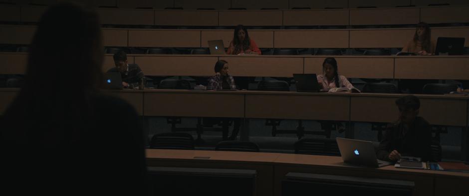 Louise looks out at the few students who show up as they are distracted by the news on their laptops.