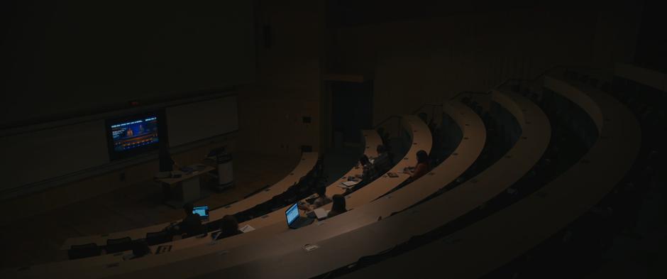 Louise turns on the news on the big screen at the front of the classroom so everyone can watch.