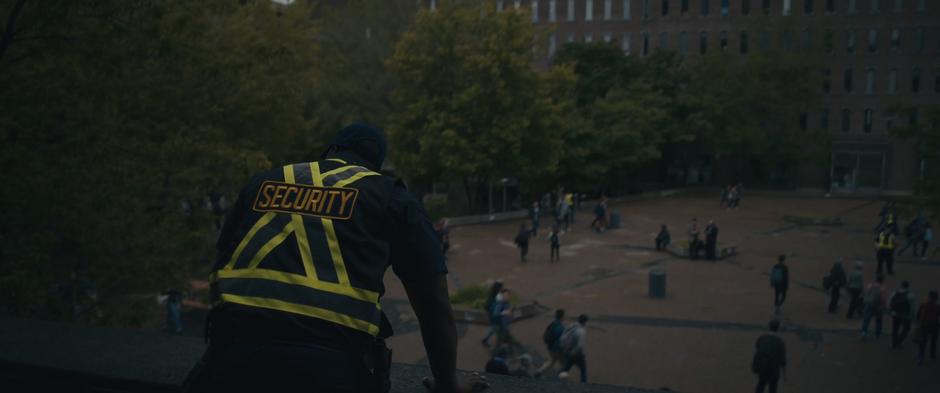 A security guard look down off the roof at the crowd below.