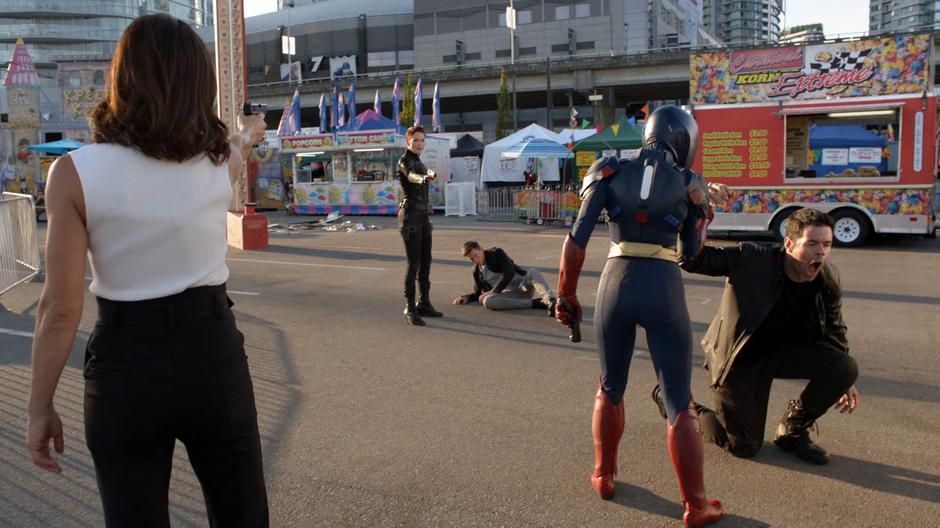 Kara stands up and disarms Otis Graves after her suit's power is restored while Mercy holds her gun on Alex who is pointing her gun at Otis.