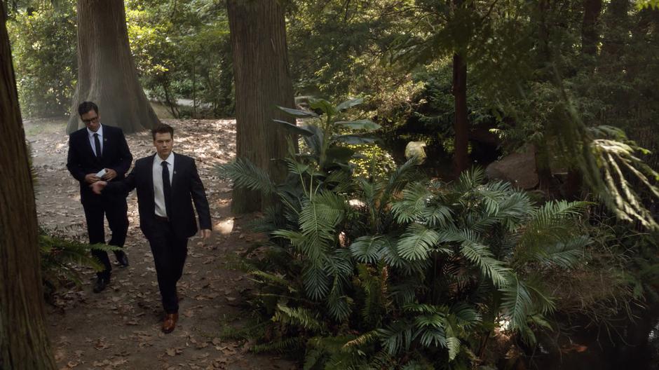 Nate talks to Gary while they search through the forest.