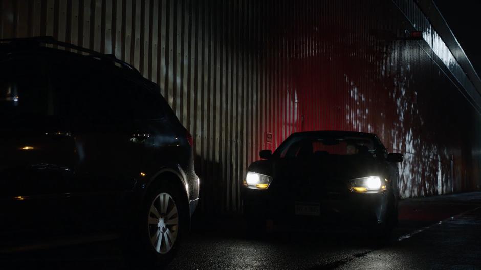 Tripp parks his car behind Mel's on the side of the warehouse.