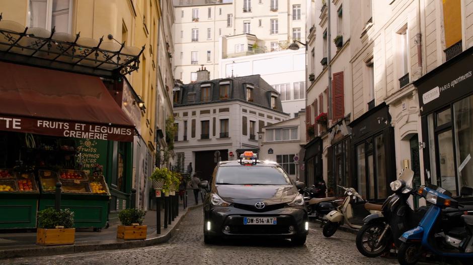 Rajan's taxi drives down the narrow street in front of the apartment building.