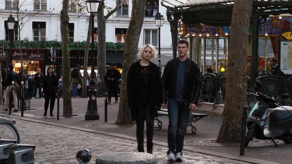 Riley and Will walk across the street away from the carousel.