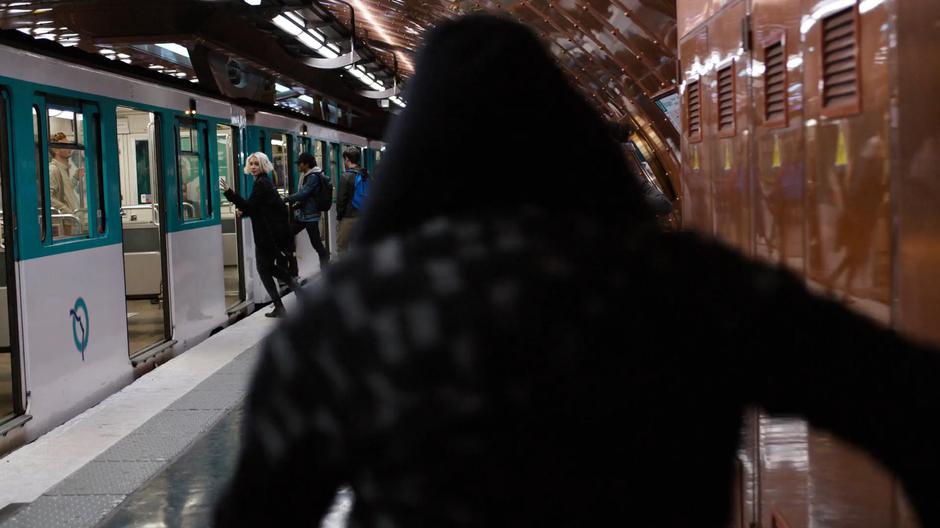 Riley glances back at the hoodied figure as she enters the train.