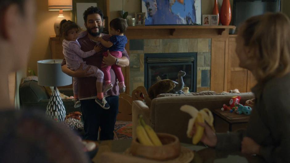 Carmen and Emma look over at Dave as he is holding his two kids in his arms.