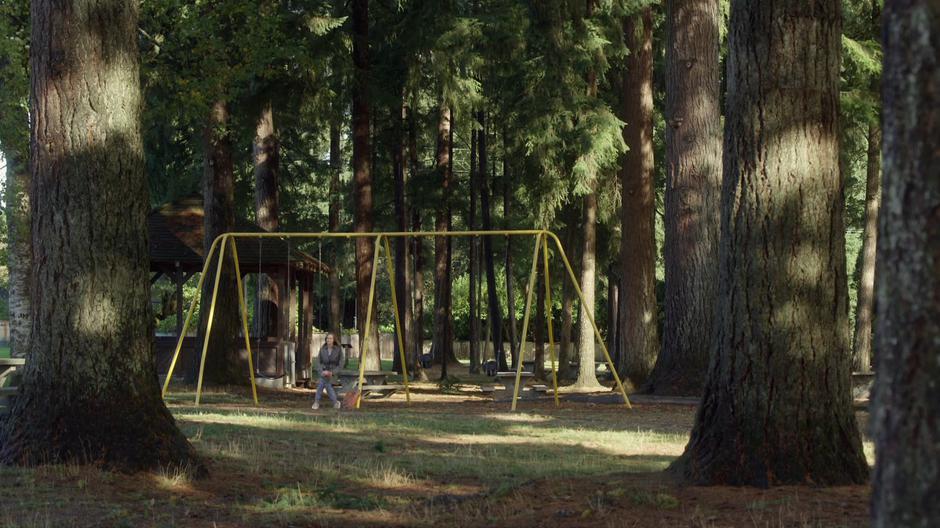 Emma sits alone on swing set in the park.