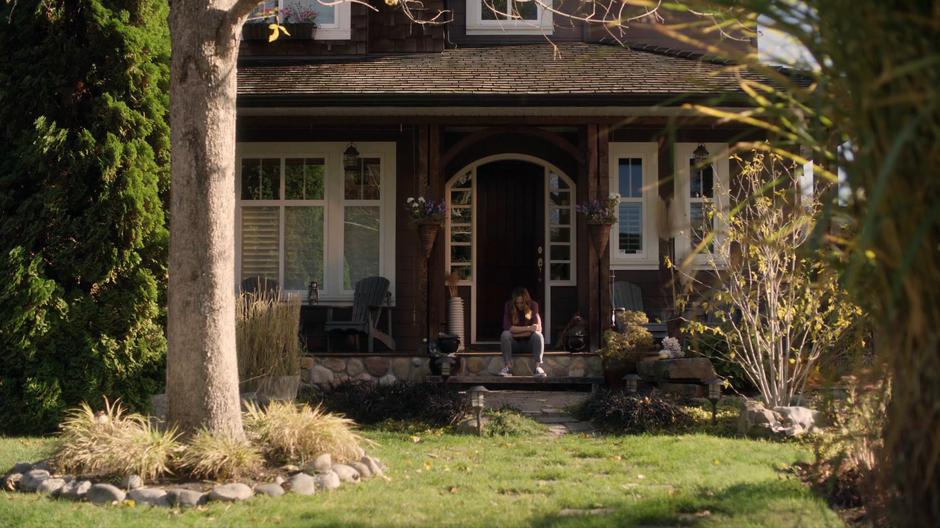 Emma sits on the porch in front of the house.