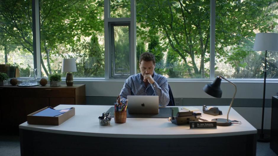 Jack sits at his desk working on his laptop.