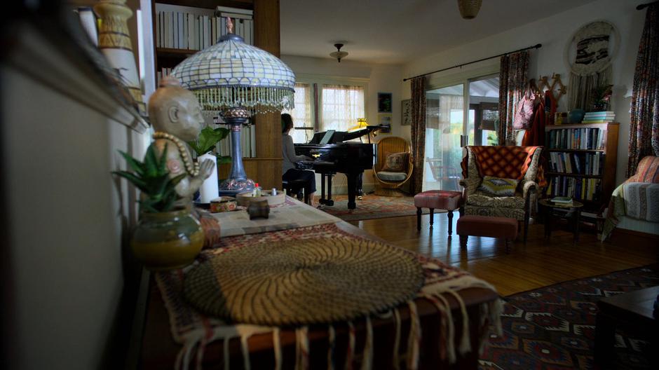 The mysterious woman sits down at her piano and prepares to play.