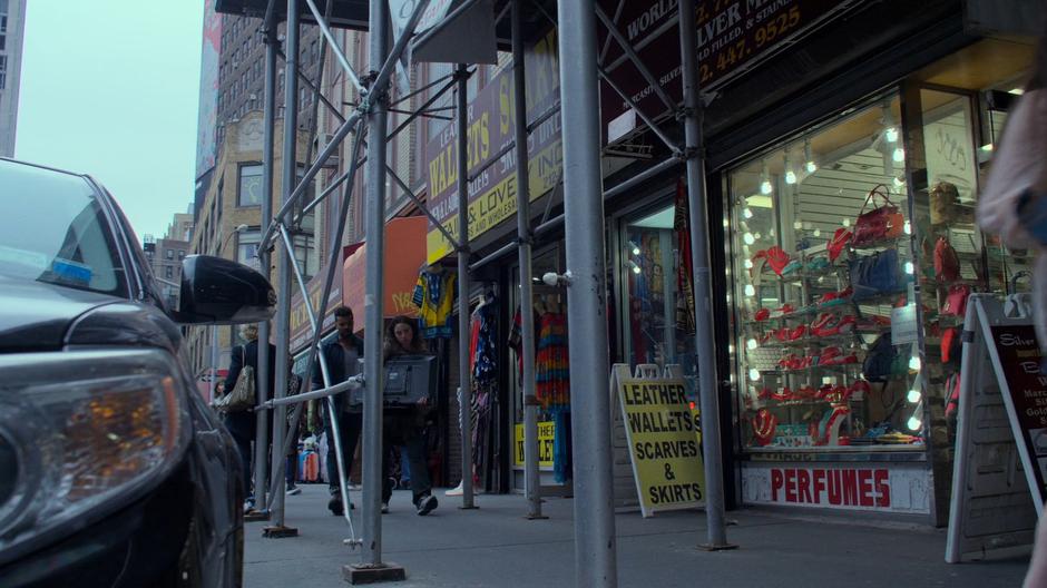 Malcolm follows Inez down the sidewalk as she carries the stolen TV.