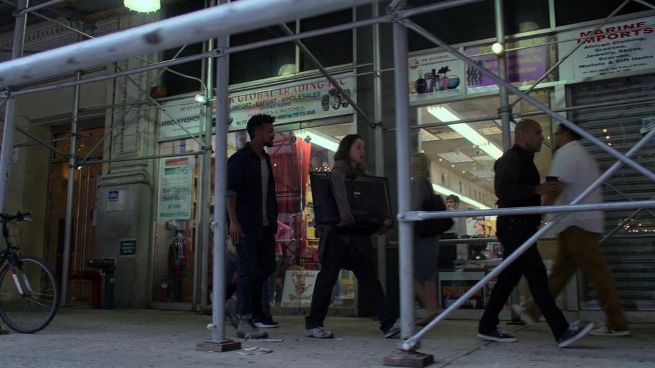 Malcolm tries to convince Inez to stop as she walks down the sidewalk with his TV.