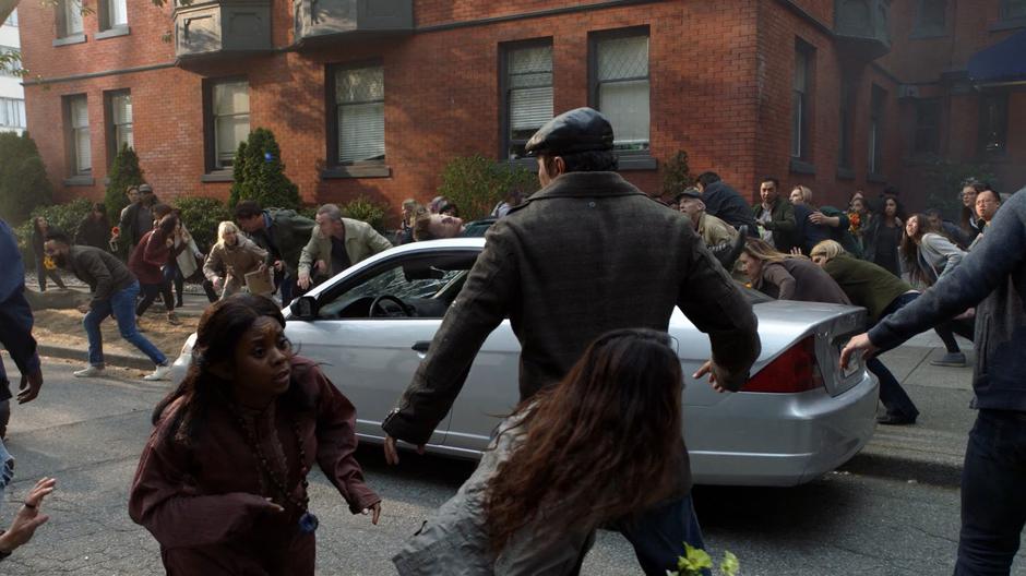 People run around as Jensen crashes down onto the top of a car.