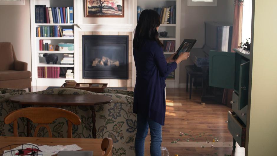 Elizabeth's mother looks at a photo of her and her daughter next to the pile of smashed glass.