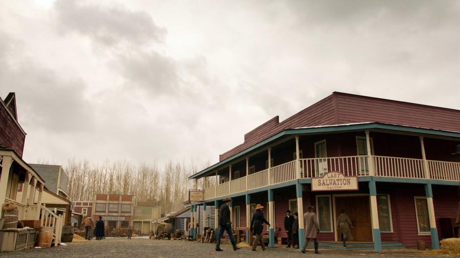 Sara, Mick, Zari, and Wally walk into the town saloon.